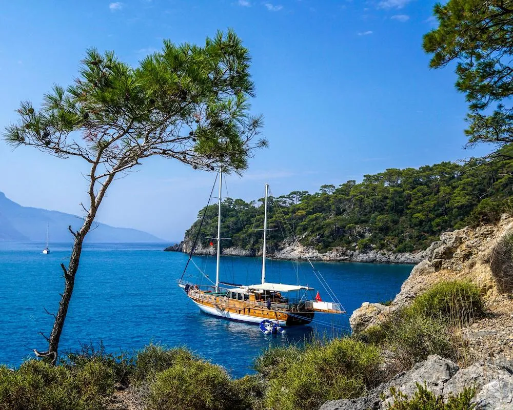 Traditional wooden boat anchored along the stunning turquoise coastline near Oludeniz, Turkey.