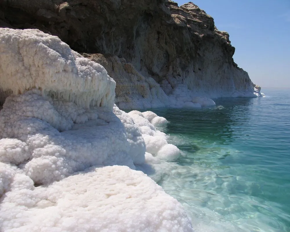 Natural salt formations on the shores of the Dead Sea under bright sunlight.